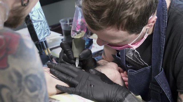 Tatooer in black gloves is making tatoo
