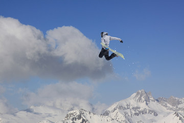 Naklejka na ściany i meble Snowboard rider jumping on mountains. Extreme snowboard sport.