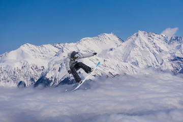 Flying snowboarder on mountains. Extreme sport.