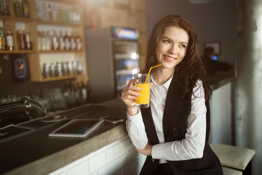 Healthy eating - young woman drinking orange juice at restaurant bar