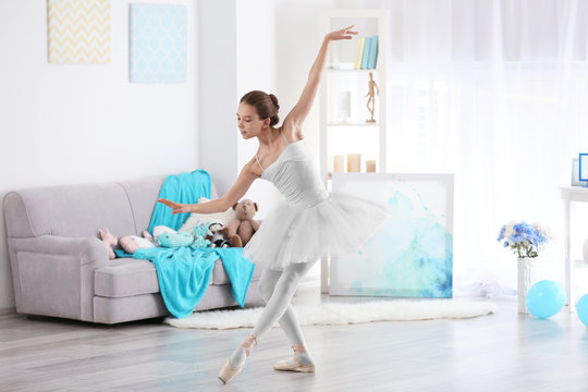 Young beautiful ballerina dancing in room