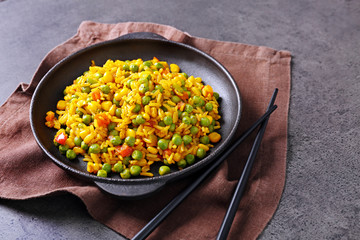 Tasty rice with vegetables in frying pan on grey table