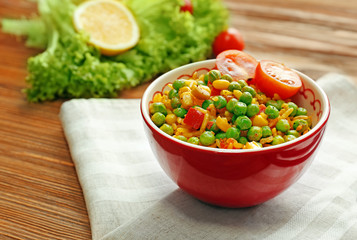 Delicious rice with vegetables in a bowl on wooden table