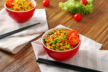 Delicious rice with vegetables in a bowl on wooden table