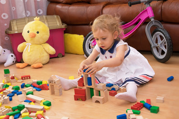 Two-year old girl playing with wooden blocks.