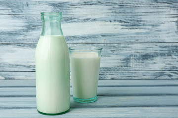 Bottle and glass of milk on wooden background