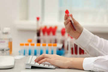 Scientist entering data of blood sample in computer at laboratory