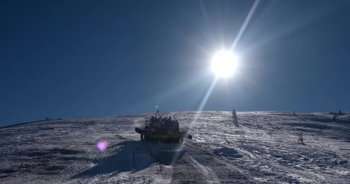 Skiers Riding on the Back of a Snowcat on a Snow Covered Mountain at a Winter Sunny Day