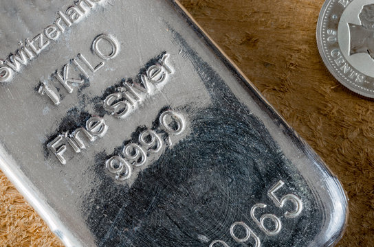 Silver Bullion Bar 1 kilo and silver coin of 50 cents on a background of a rough wooden texture. .