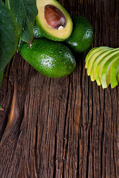 Avocado split in half on old wooden table with free space for your text. Top view.