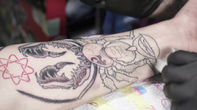Closeup of tatooer in black gloves is making tatoo