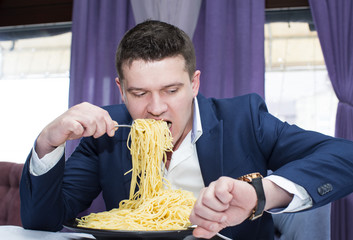 A man in a business suit eating spaghetti