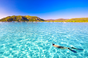 Young attractive man snorkeling in green lagoon in Santa Giulia sandy beach, Corsica, France