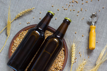 Two glass bottles of beer. Ceramic plates with wheat. wheat spikelets