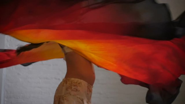 A female performer twirling with colorful fabric wings smiling in slowmo