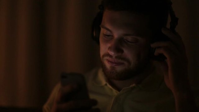 man with smartphone and headphones at night