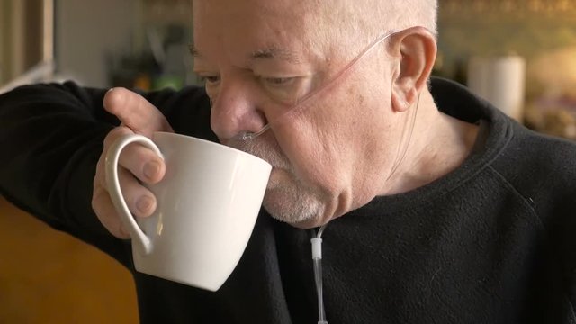 A Senior Man Drinking Coffee While Wearing Oxygen Mask In Slowmo