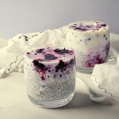 Chia pudding with blueberry sauce and jam in glasses on white background, healthy breakfast.