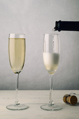 Pair of Fluted Champagne Glasses Being Filled on Wood Plank Table