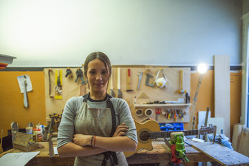 woman luthier small business owner portrait, in her musical instrument workshop - obrazy, fototapety, plakaty