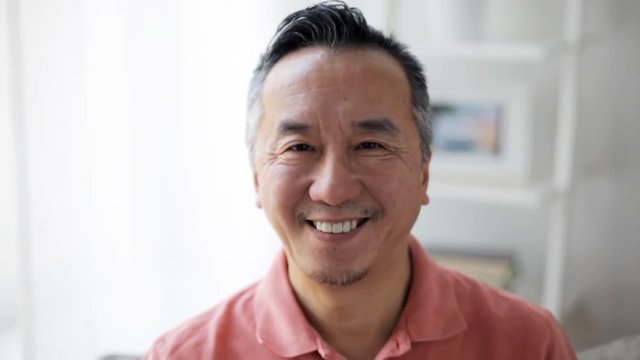 face of happy smiling asian man at home