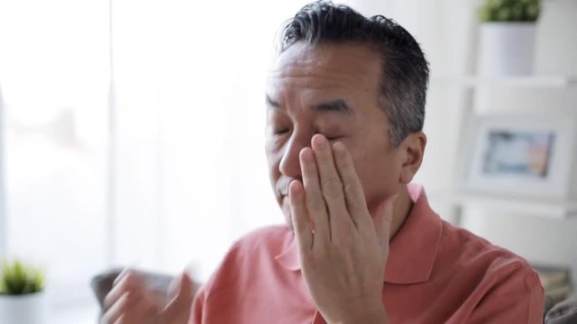 Tired Man In Glasses Rubbing Eyes At Home