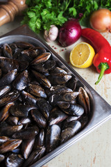Fresh mussels with ingredients for cooking on rustic background, top view, border. Seafood concept.