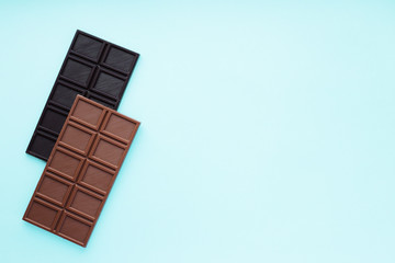 Two bar of chocolate, dark and milk on blue background