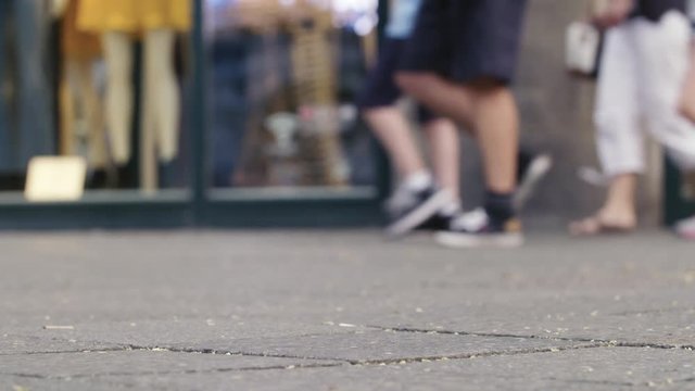 Low Angle Slow Motion Shot in a Shopping Street, Slow Motion Shot in front of a Shop. Its a low angle shot, showing only the legs of the passing Pedestrians. 