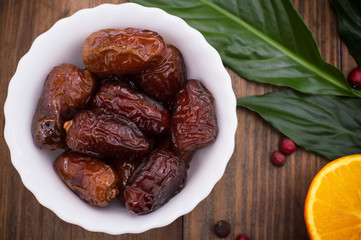 Dried dates exotic fruit on a plate in a rustic style. Wooden background. Top view. Close-up