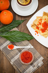 Pancakes with red caviar. Russian cuisine. Flat lay. Maslenitsa. Wooden background. Top view. Close-up