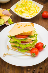 Big sandwich, meat, lettuce, cheese and vegetables on toasted. Wooden background. Close-up
