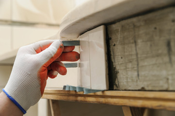 Worker's hand wedges tile.