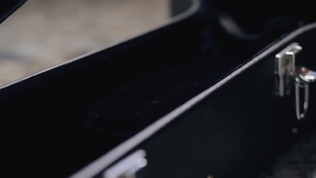 Closeup of guitarist gets a guitar out of the case