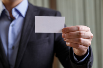 Businessman holding visit card. Man showing blank business card. Person in black suit. Mock up design.