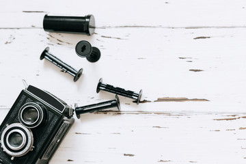 Retro camera, old photo film rolls  on white wooden background. top view