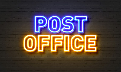 Post office neon sign on brick wall background.