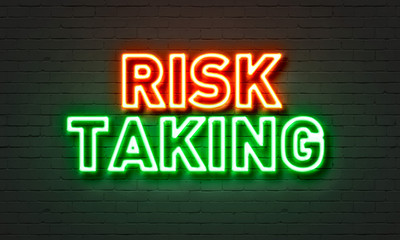 Risk taking neon sign on brick wall background.