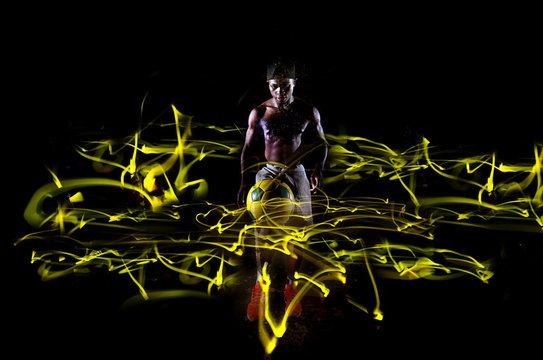 Black man playing soccer over a black background