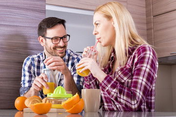 Young couple have fun in kitchen while preparing fresh orange juice and breakfast