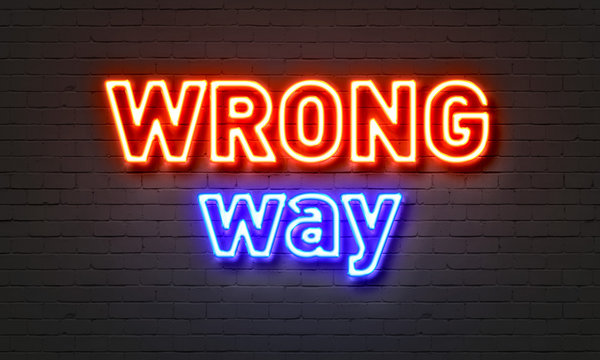 Wrong way neon sign on brick wall background.