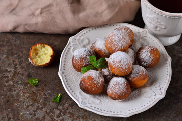 Homemade donuts with powdered sugar for breakfast on the old grunge background