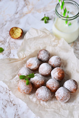 Homemade donuts with powdered sugar and milk on a marble background