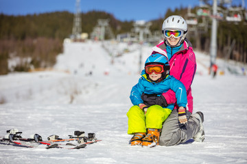 Cheerful mother and son resting on ski slope