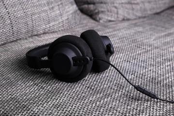 Headphones lying on sofa. Musical concept. Modern device for listening music. Sound earphones on couch.