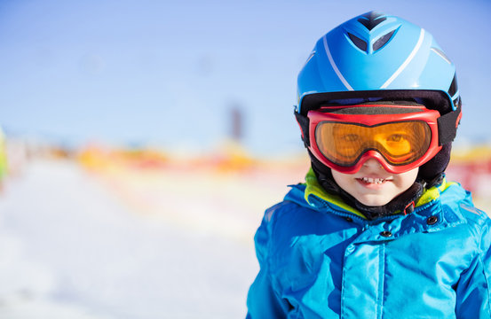 Cheerful young skier wearing safety helmet and goggles