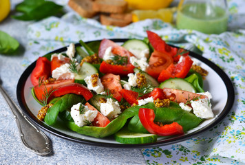 Vegetable salad with tomatoes, spinach and feta cheese on a concrete background.