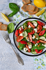 Vitamin salad with tomatoes, spinach and feta cheese on betonnoom background. Top view.