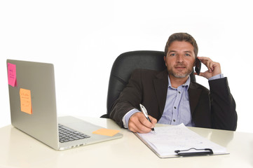 businessman in suit working at laptop computer desk talking on mobile phone at modern office