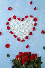 Heart of red rose petals on blue painted rustic background. Valentines day or love concept. Fresh natural bouquet of flowers.